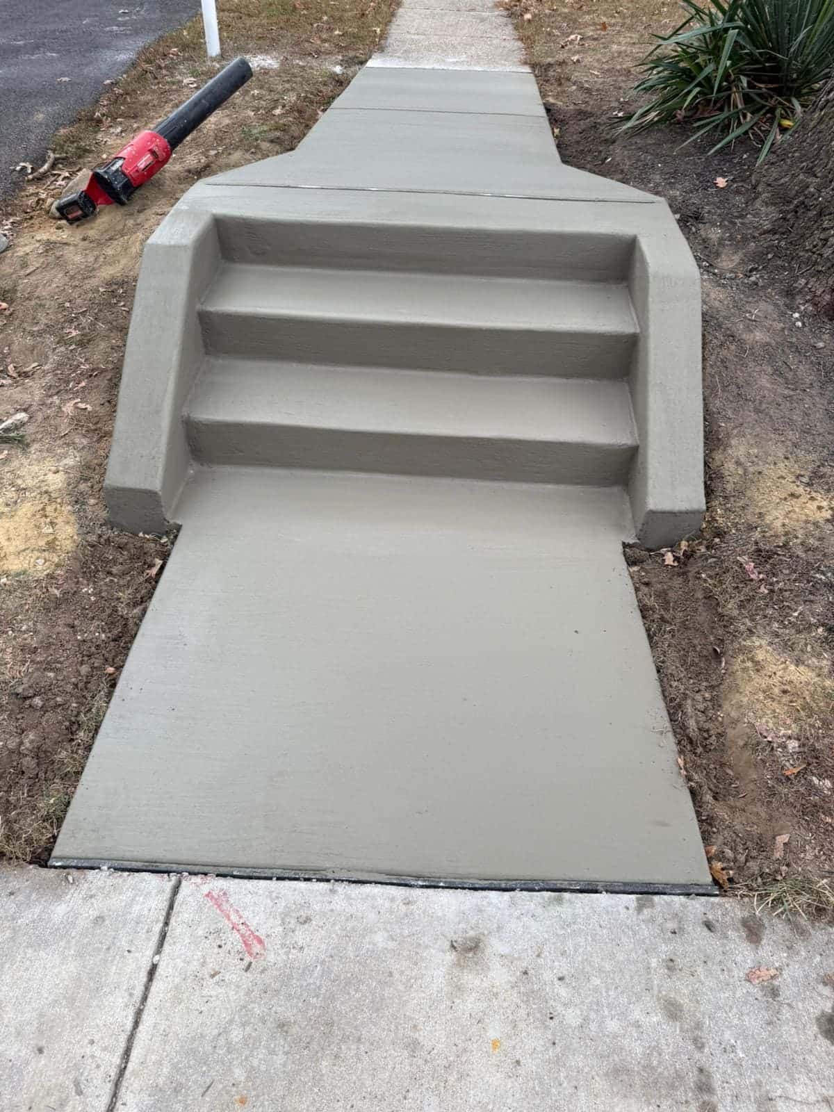 New broom-finished concrete steps with a landing and a wide walkway apron, freshly poured