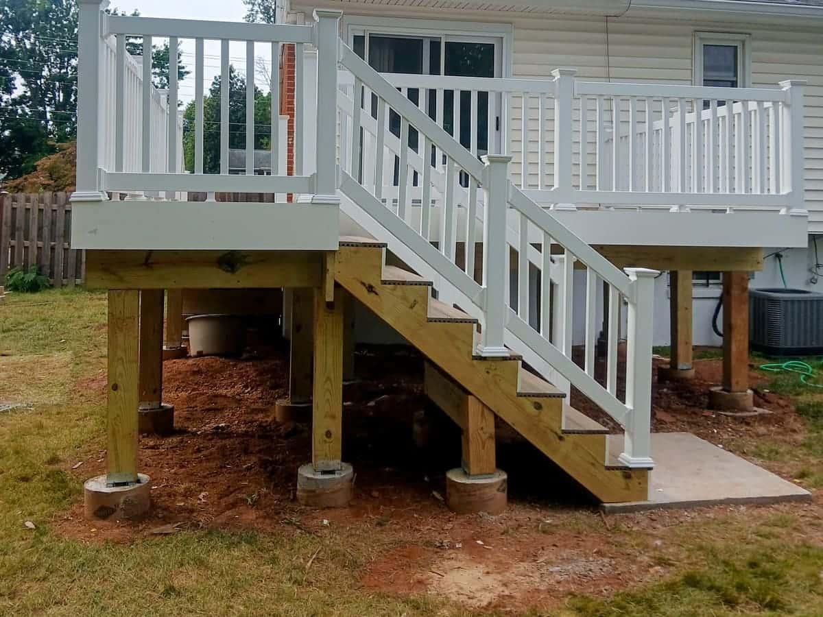 Deck rebuilt by Roso with white vinyl railing, a long stair run, and new pressure-treated framing on a split-level home